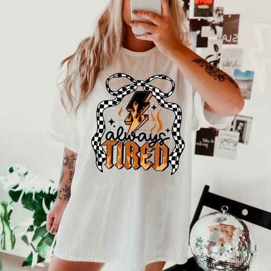 Always Tired Graphic Tee – Funny Relatable Checkered Bow Shirt | Retro Lightning Bolt Design