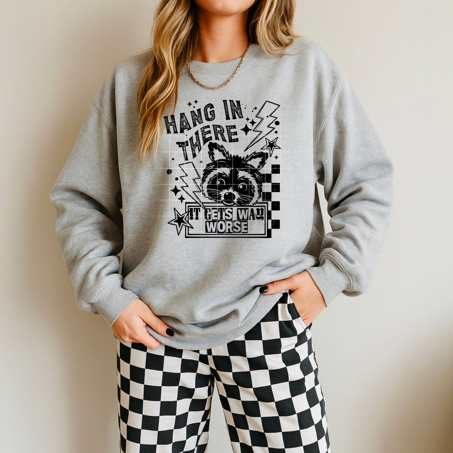 🦝 “Hang In There… It Gets Worse” Sweatshirt – Funny Raccoon Graphic Crewneck | Retro Checkered Design | Unisex Cozy Pullover